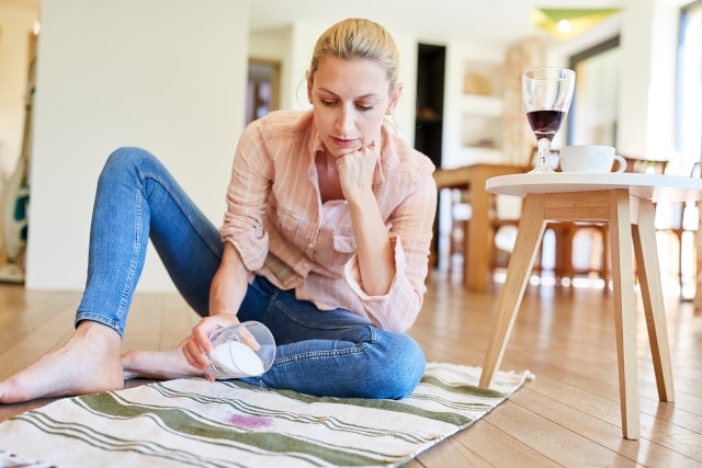 Frau entfernt Rotweinflecken mit Salz aus dem Teppich